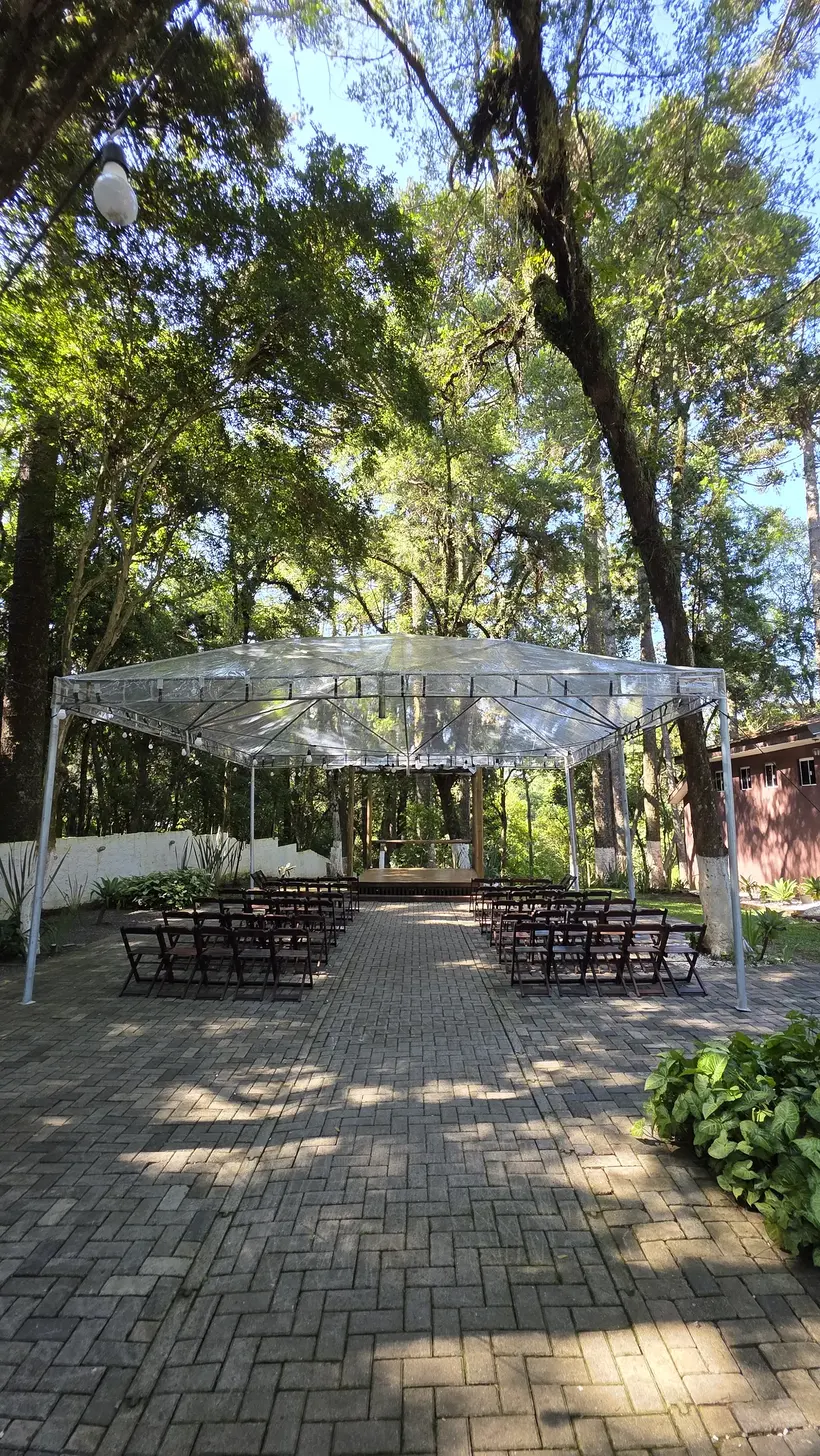 Gazebo de cobertura transparente no jardim, com mesas embaixo
