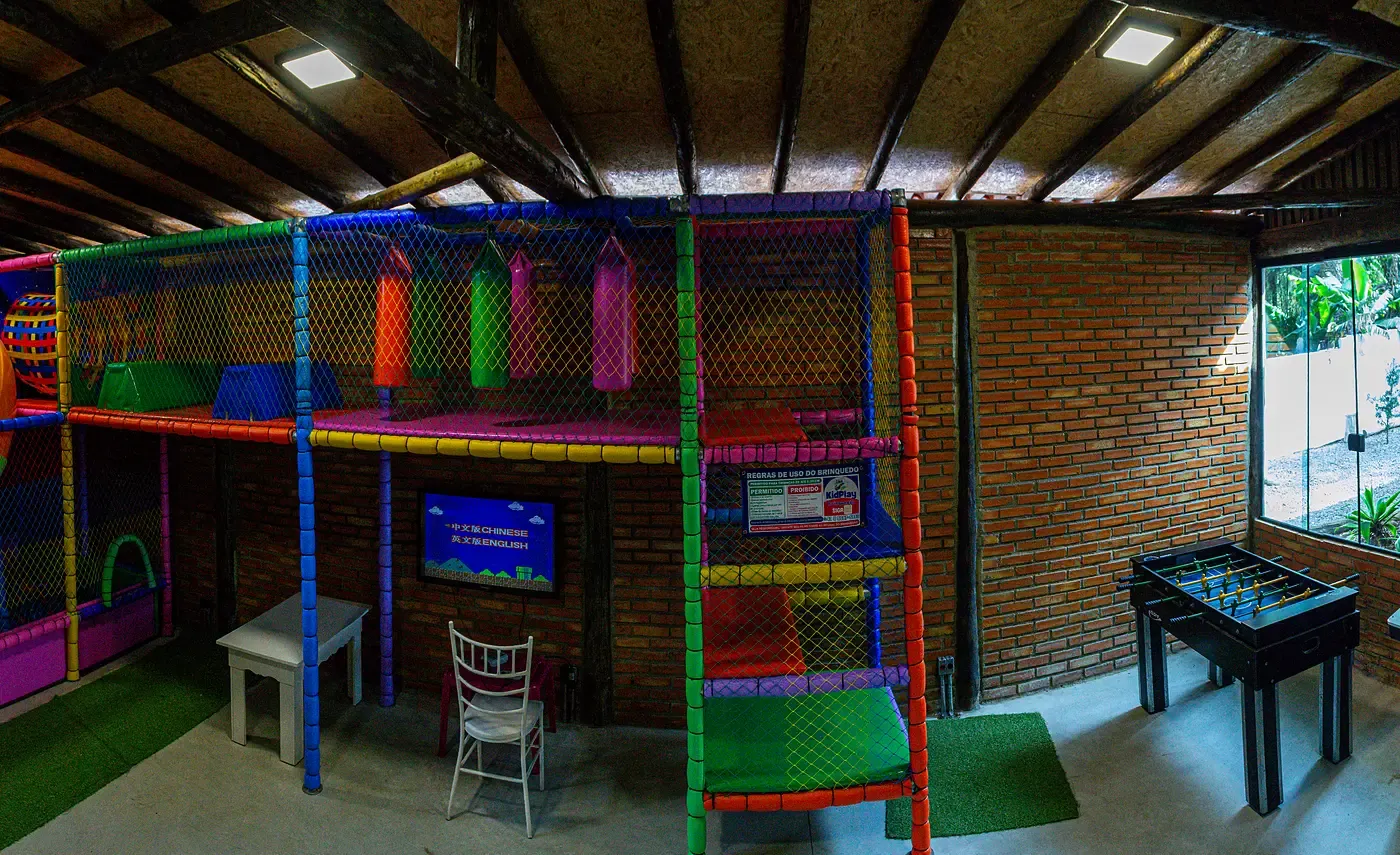 Espaço kids com brinquedão colorido, fliperamas e pebolim