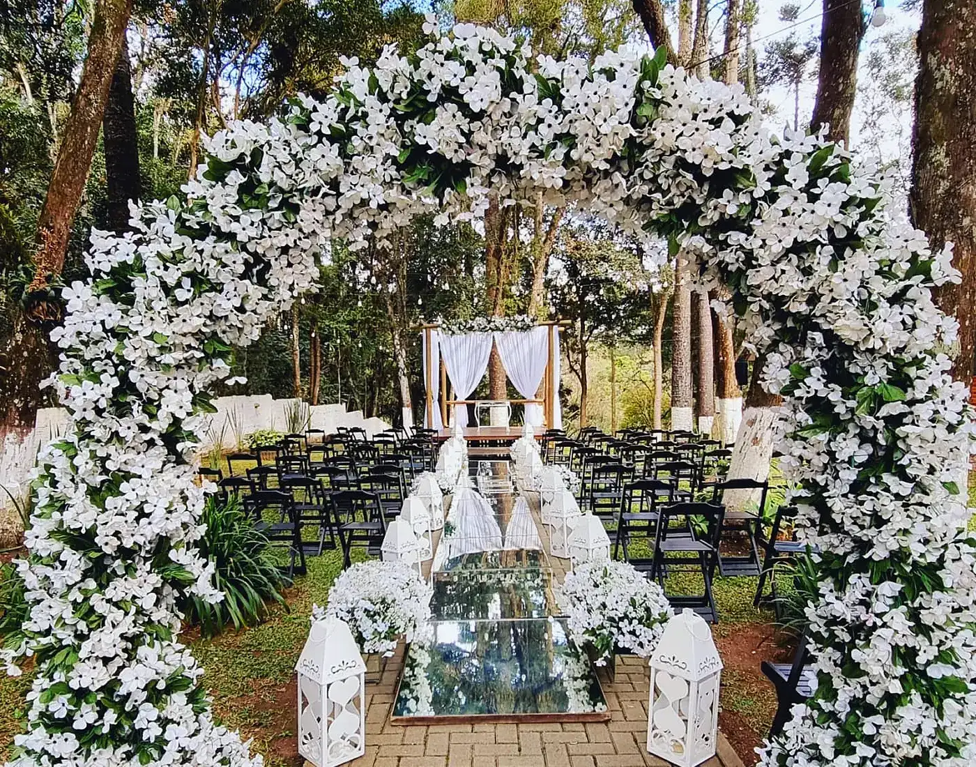 Arco de flores brancas e cadeiras montadas para a cerimônia no bosque, à tarde