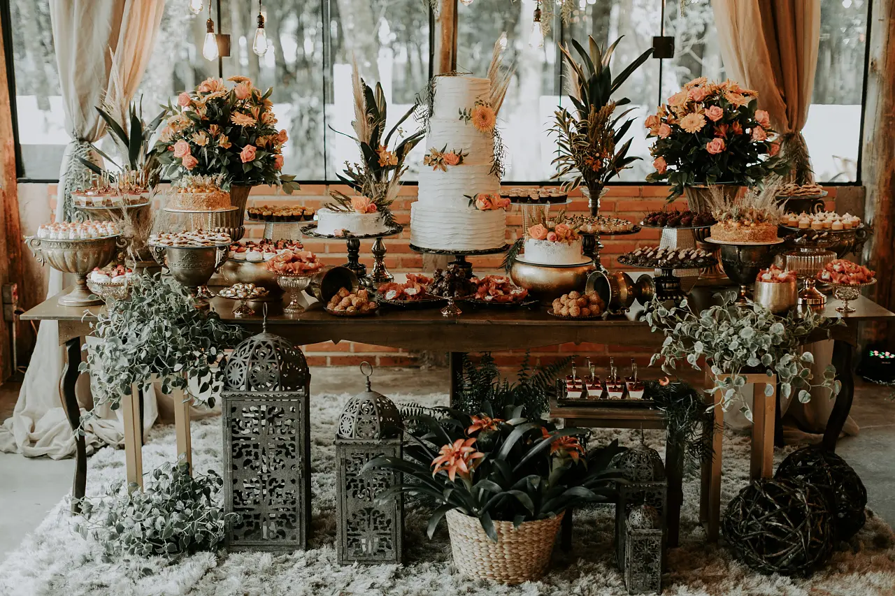 Mesa de doces e bolo decorada com flores no salão