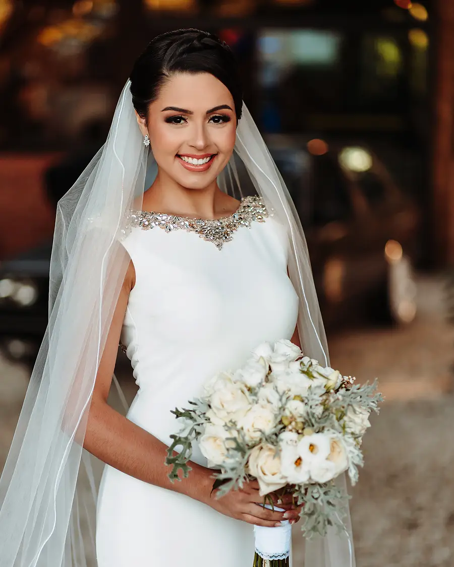 Noiva sorrindo com buquê de flores brancas