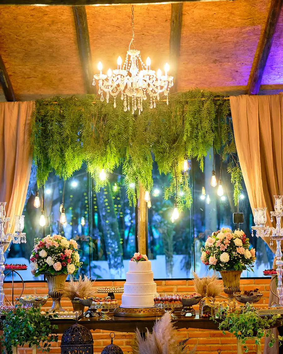 Salão decorado com lustre e cortina de folhagens