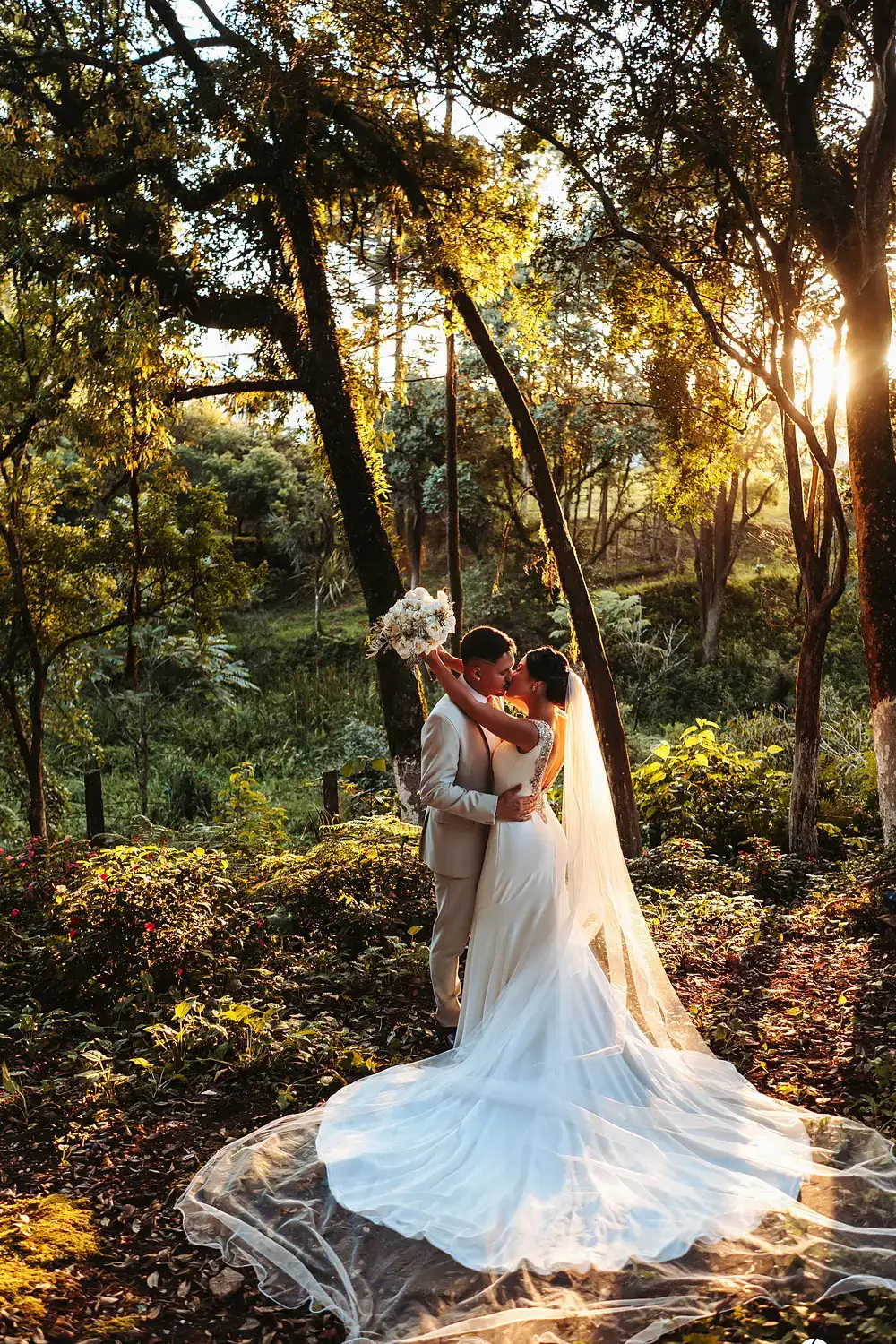 Casal de noivos no bosque com o sol do fim da tarde atravessando as árvores